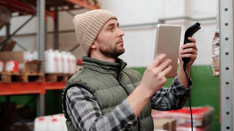 Barcode scanner types in use as a handheld reader captures stock codes in a warehouse