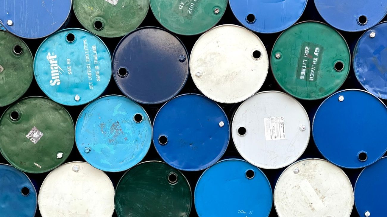 Weathered steel drums showing faded and lifting chemical drum labels outdoors