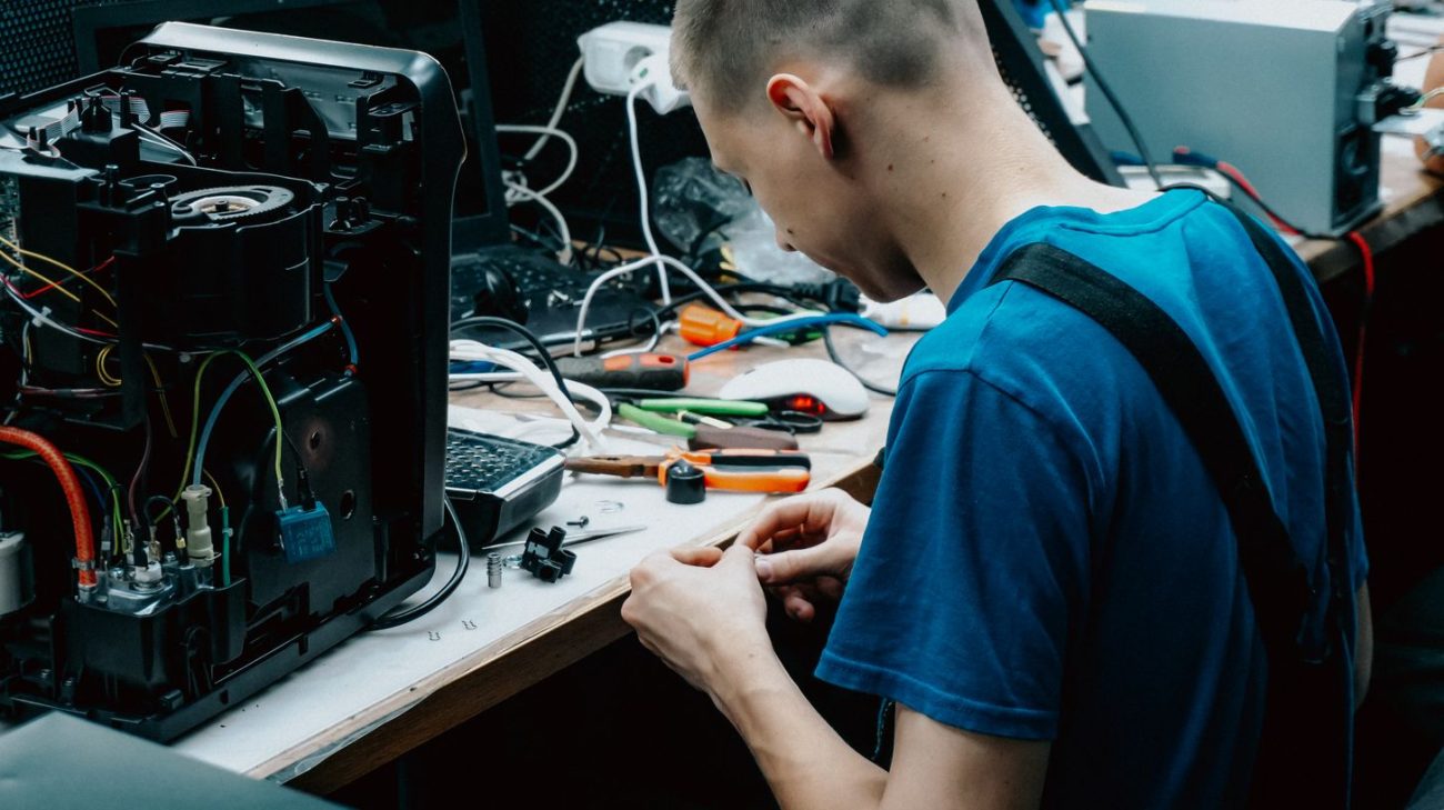 Electronics technician working at a repair bench with fine tools