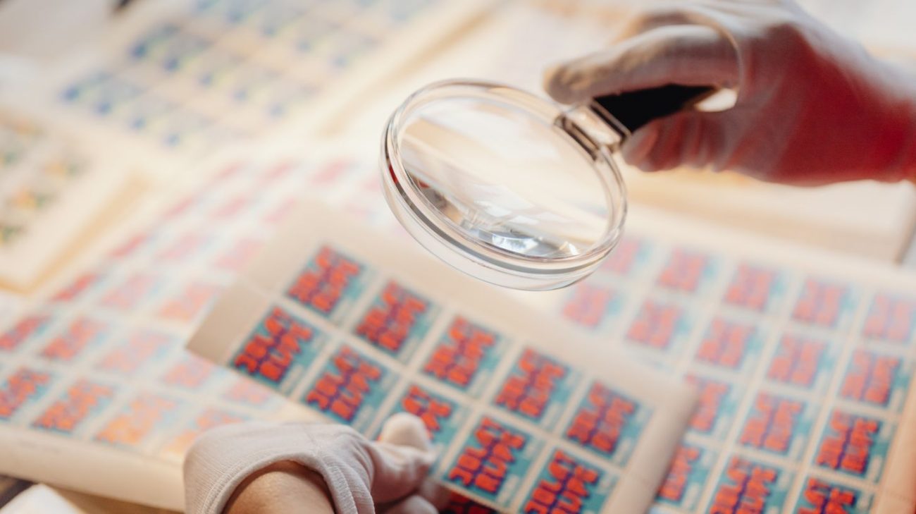 Inspecting a printed sheet with a magnifying glass to judge barcode print quality