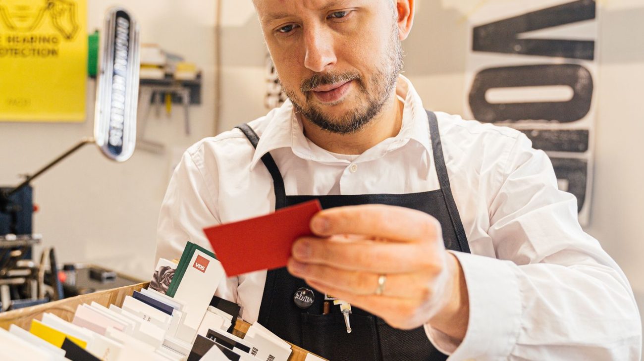 Print studio worker inspecting freshly printed cards for quality
