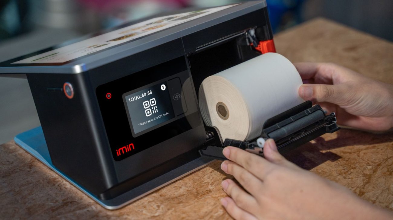 Hands loading a thermal label roll into a printer