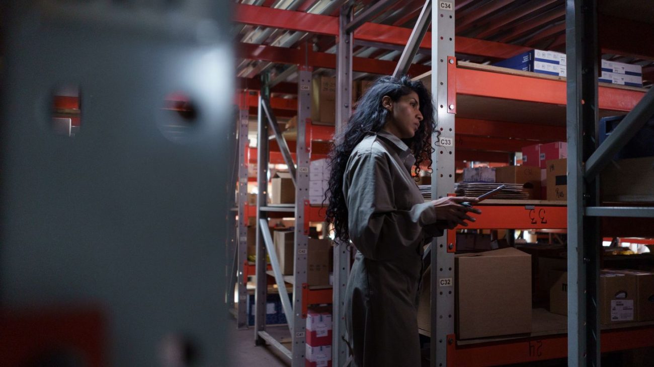 Operator checking inventory with a mobile barcode reader between racks