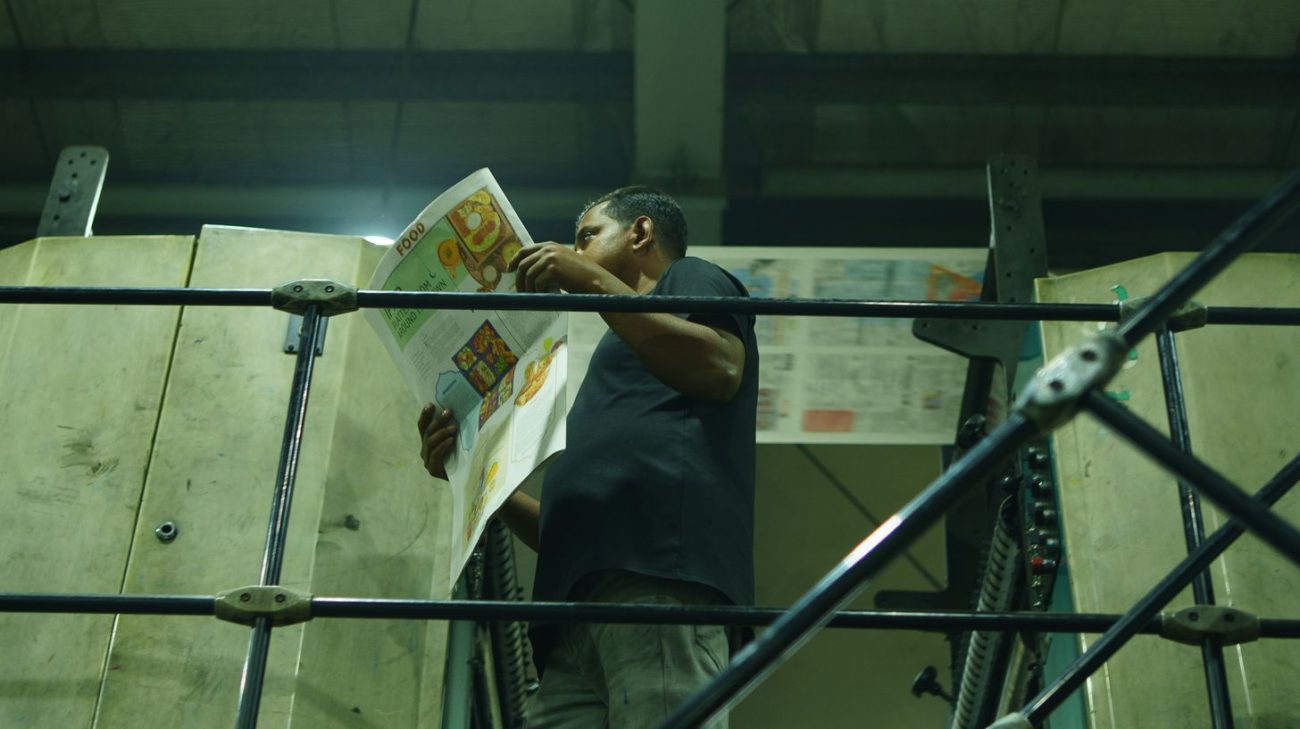 Press operator checking printed output for defects that lower barcode grades
