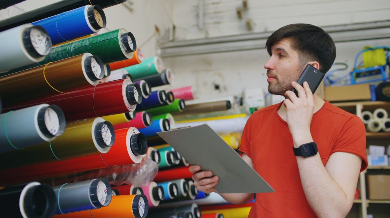 Print shop operator checking a job list on a clipboard