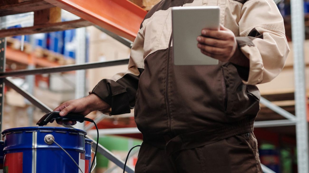 Worker recording read results on a tablet beside racking