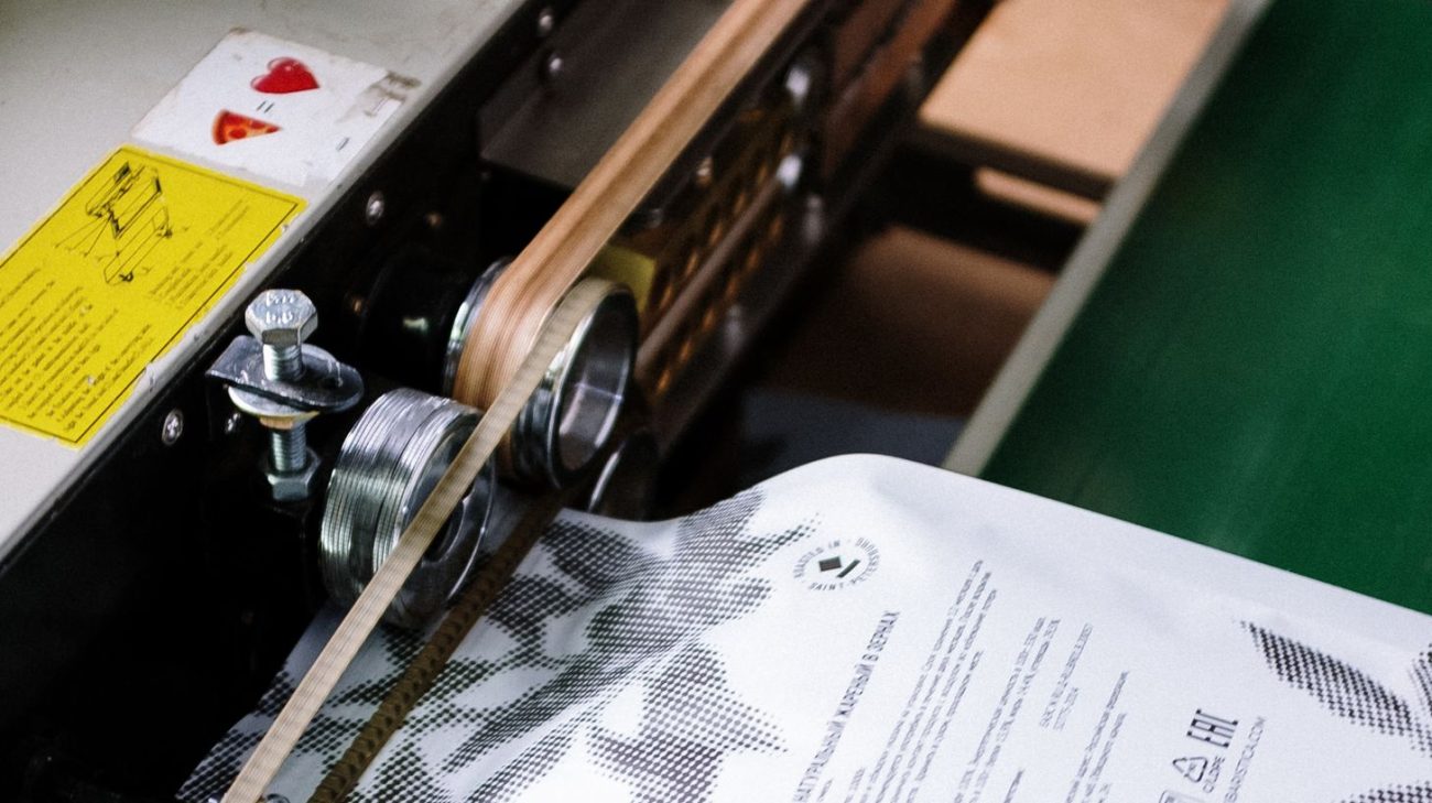 Sealing machine closing a filled bag beside the coding station