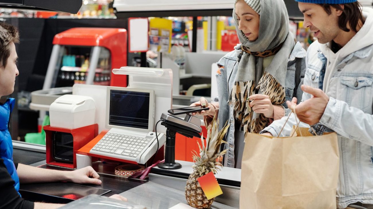Customer paying at a modern supermarket checkout where product codes are scanned