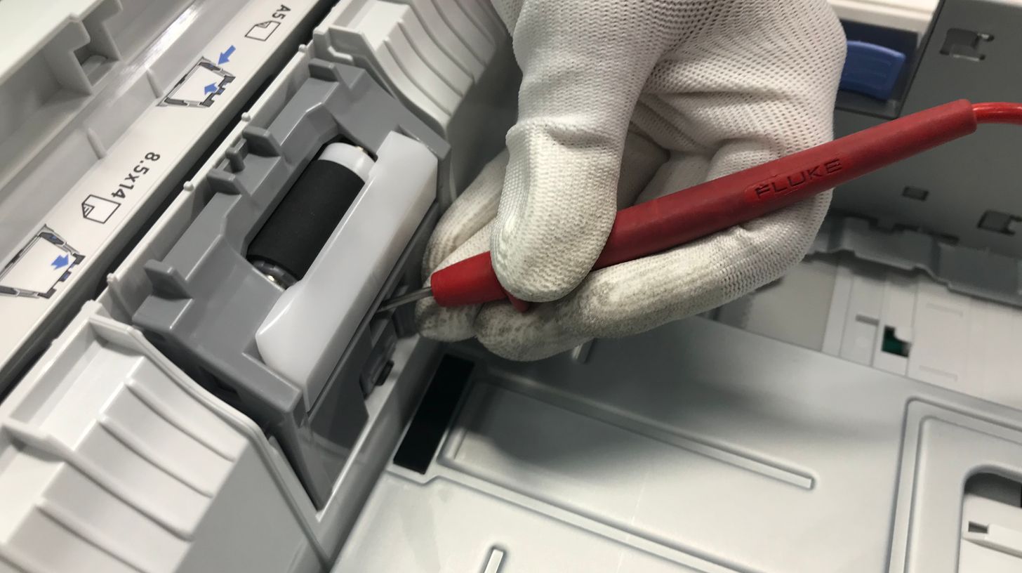 Technician carrying out thermal printhead maintenance inside a label printer with a precision tool